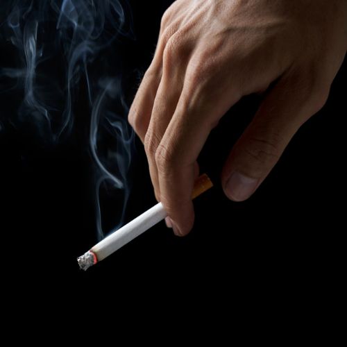 cigarette smoke coming from hand on black background