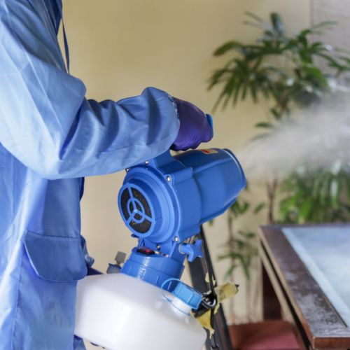 blue suit spraying disinfecting mist onto desk