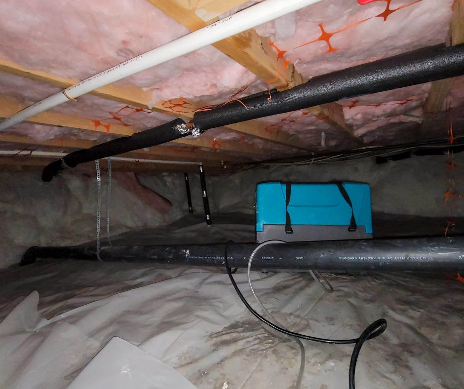 a dehumidifier in a crawl space under wet pink insulation