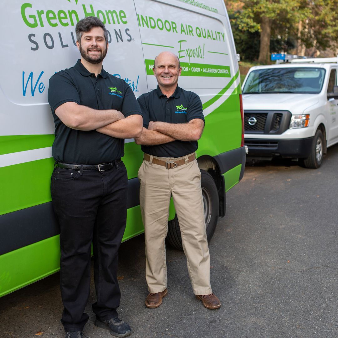 two men in black polo shirts standing in front of a van